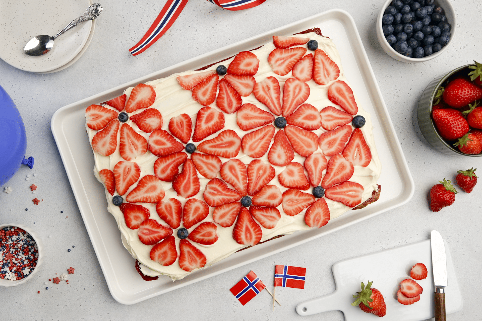 Rød marmorkake med kremostglasur, pyntet med jordbær formet som blomster