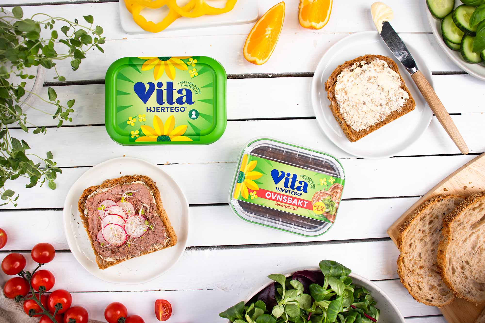 vita hjertego original og leverpostei, omgitt av påsmurte skiver, paprika, appelsin og tomater